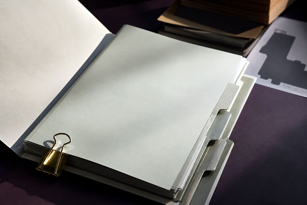 A neatly labeled source ledger, bookmarked government publications, and a brass paper clip
